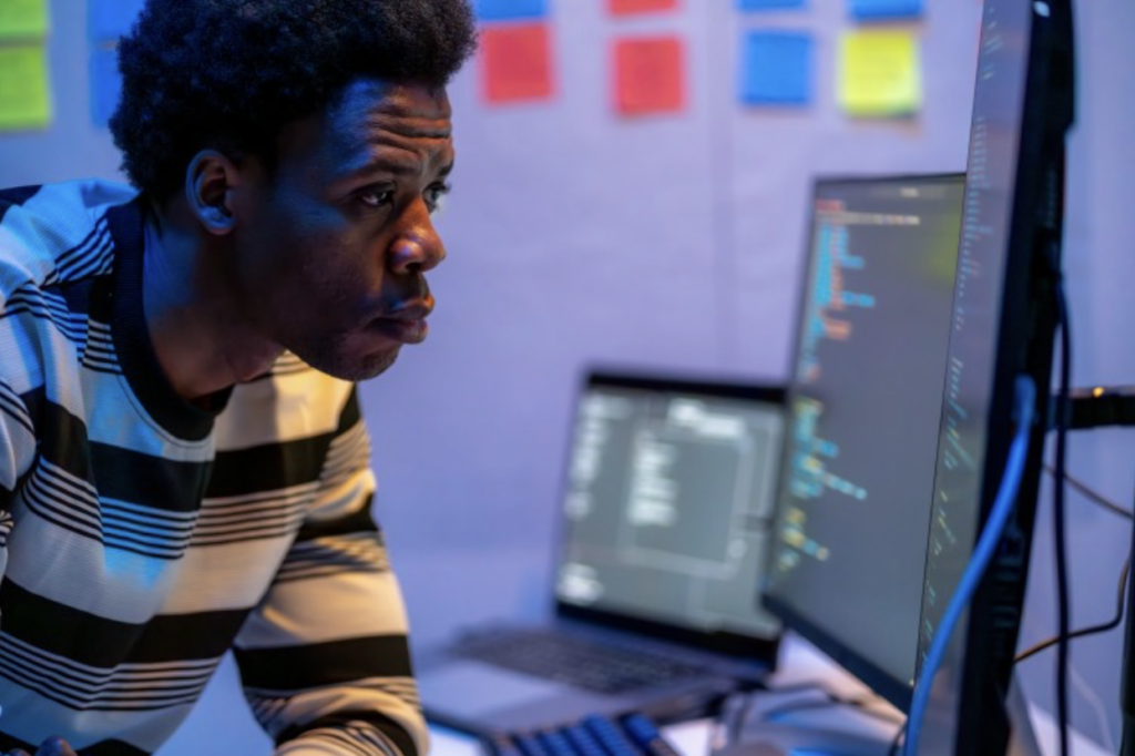 An information security analyst working at a desk with three computers.